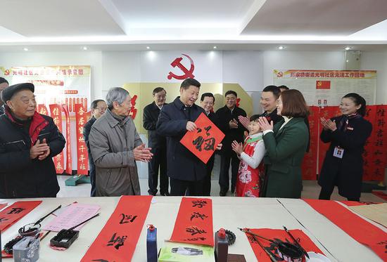 2016年2月3日，習近平在南昌市東湖區彭家橋街道光明社區書畫室，接過一位小朋友現場書寫的 “?！弊?，祝大家都幸福。新華社記者 蘭紅光 攝